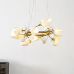Lit Clérachic ring chandelier seen from below, with white petals and buds on twisting gold branches, against a pale wall.