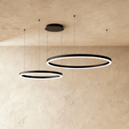 This Clérachic ring chandelier stacks two black loops at different heights against a warm plaster backdrop.