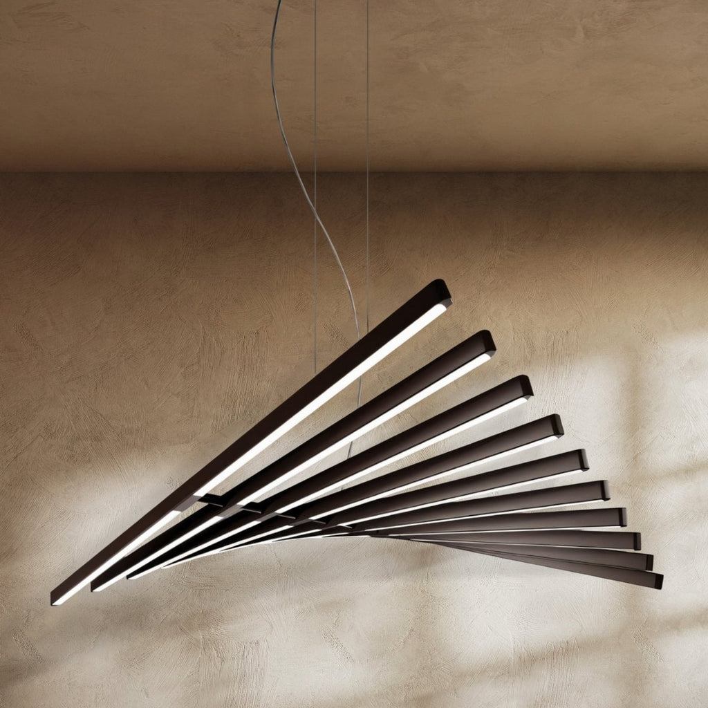 Clérachic's black bar chandelier fans in a sweeping curve, its LED bars glowing against a warm plaster wall.