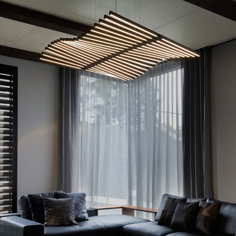This Clérachic bar chandelier spans a living room ceiling, its dark bars glowing above a leather sofa.