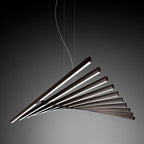 Clérachic's black bar chandelier fans its glowing bars against a dark backdrop in profile view.