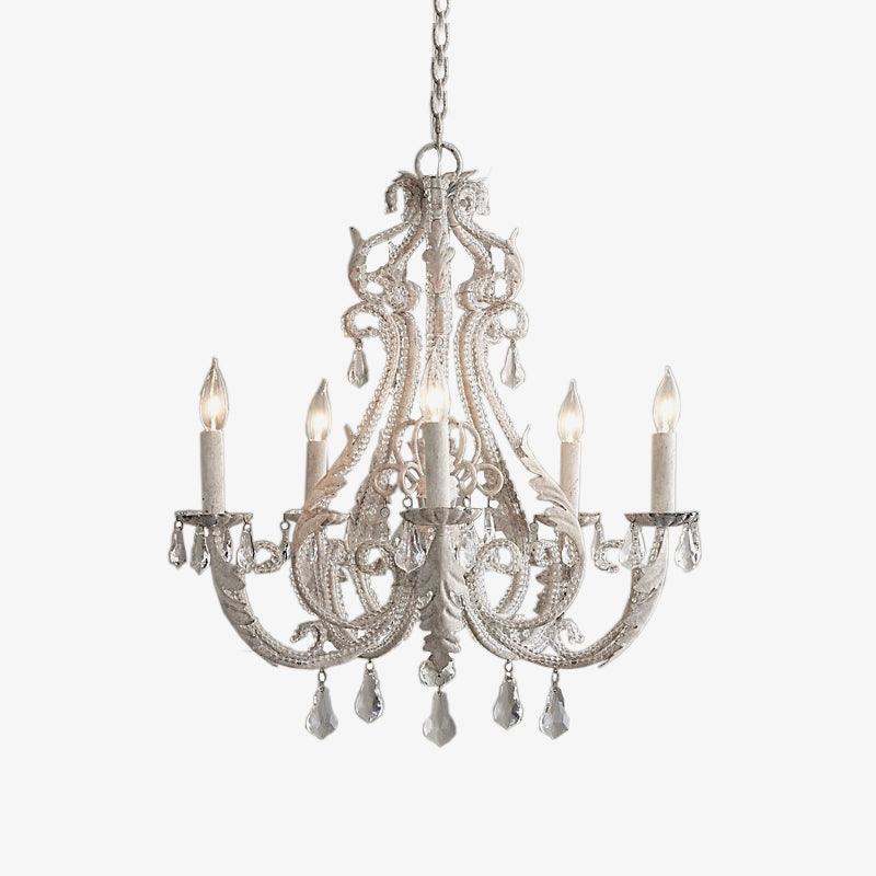 A Clérachic candle-style chandelier with scrolling white metal arms, crystal drops and candle sleeves, on a plain white backdrop.