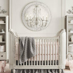 A Clérachic chandelier mounted in front of a round lattice wall panel, above a white cot with a grey throw.