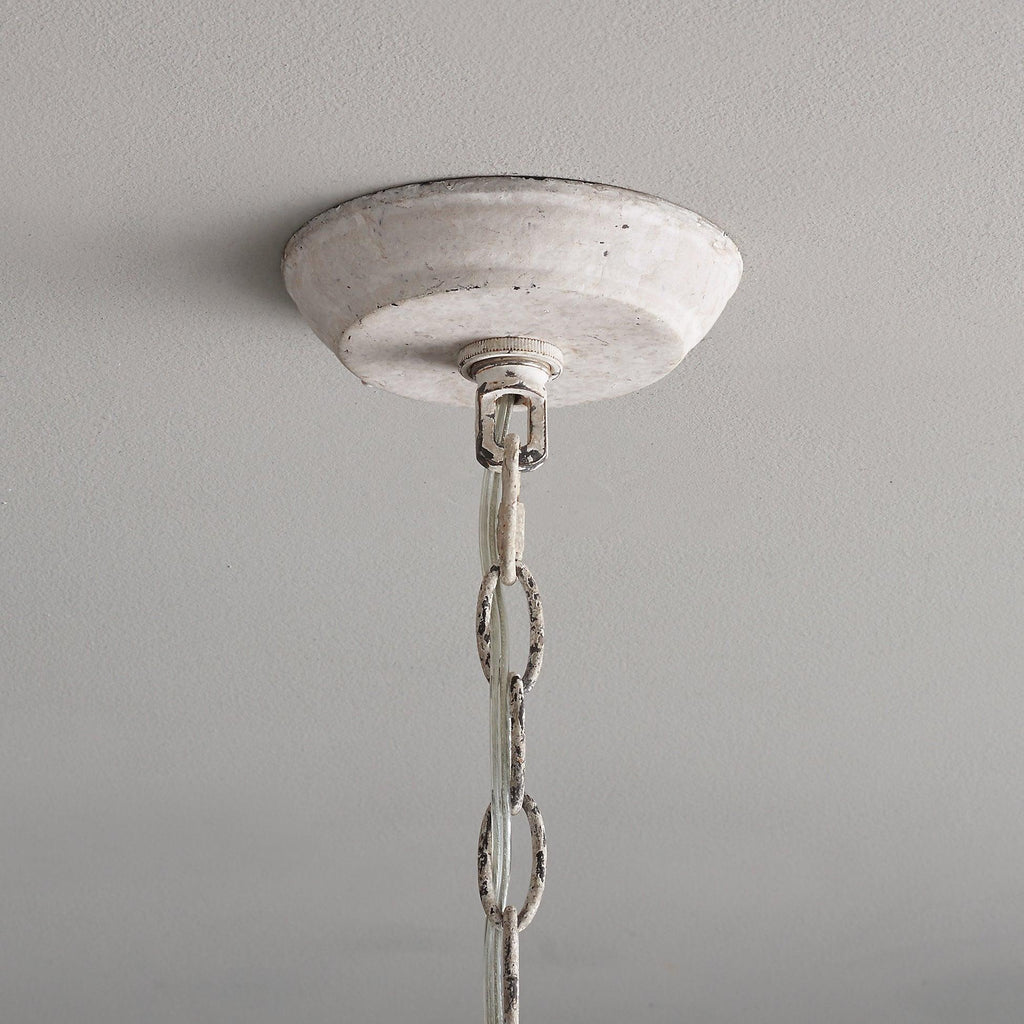 Close view of the round, chalky white ceiling canopy and the first links of the chain on this Clérachic chandelier.