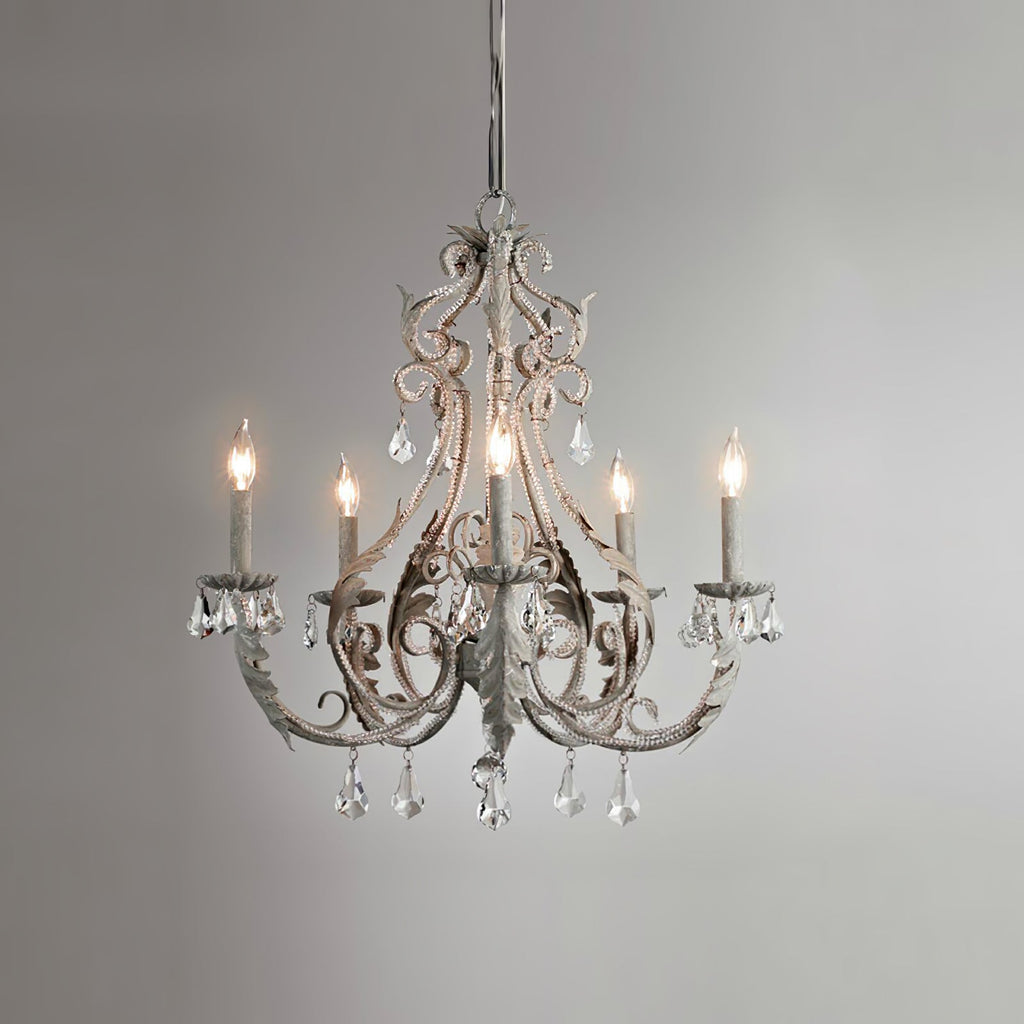 A Clérachic chandelier in an aged grey-white finish, with unlit candle sleeves, on a grey gradient backdrop.
