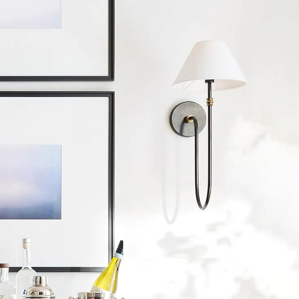 Black Clérachic wall light with a white tapered shade on a bright wall, with framed art and a bar tray at the left.