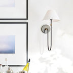 Black Clérachic wall light with a white tapered shade on a bright wall, with framed art and a bar tray at the left.