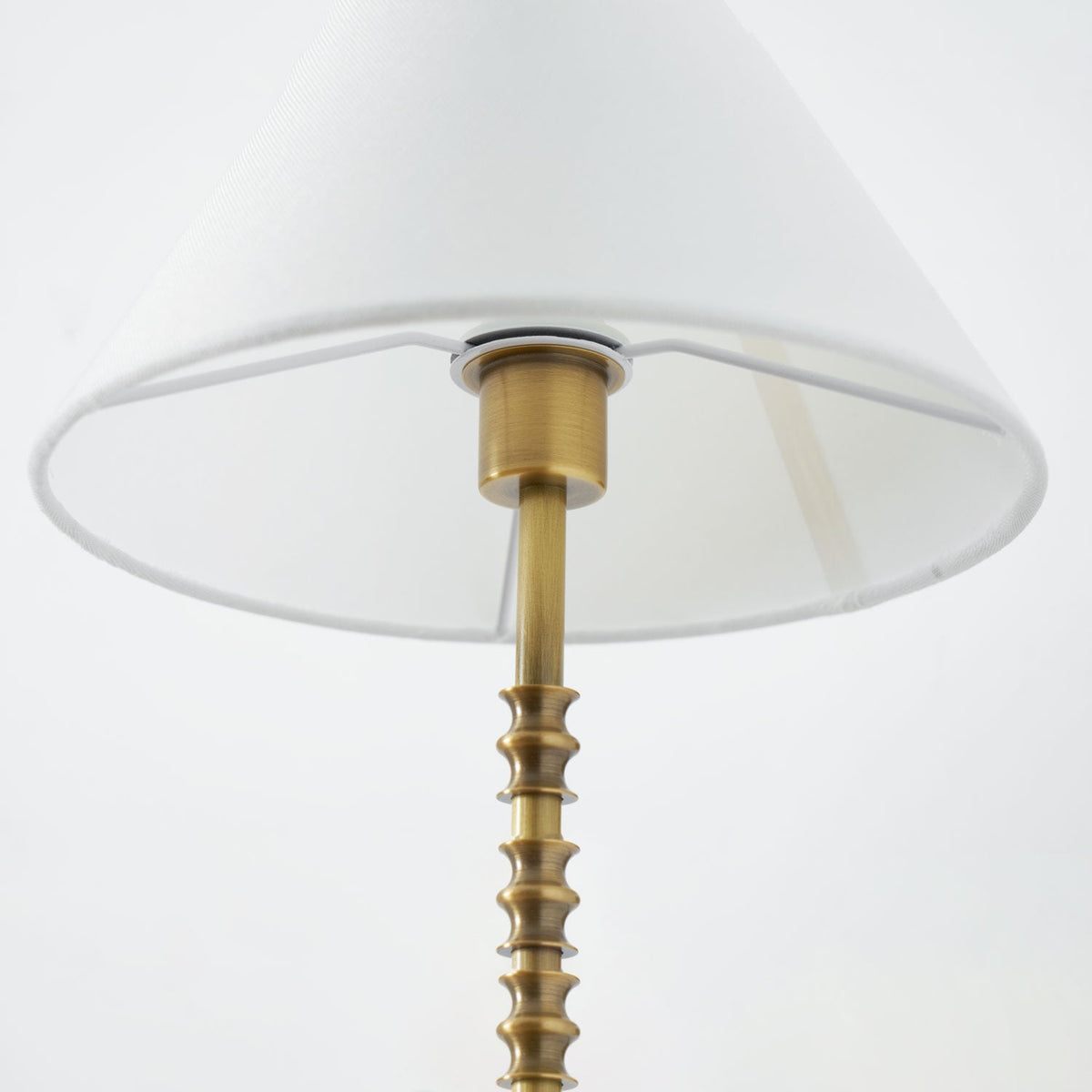Close view up inside the white fabric shade of this Clérachic wall light, showing the brass socket and ridged stem.