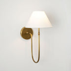 Brass Clérachic wall light with a white fabric shade and a deep curved arm, close and slightly angled on a pale wall.