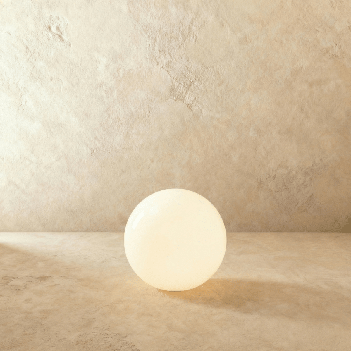 This Clérachic sphere floor lamp glows warm and bright, its light spreading across the plaster floor.