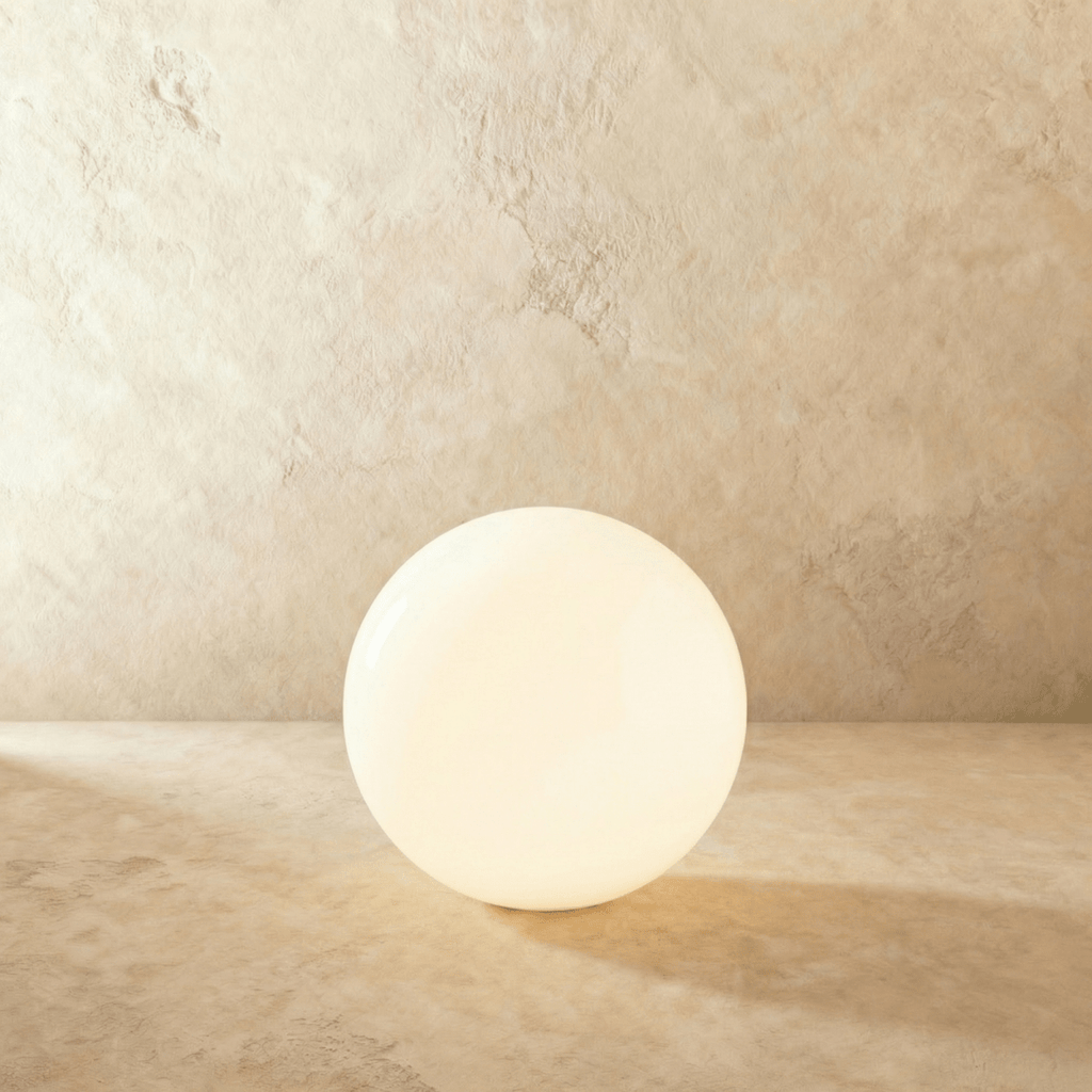 A large Clérachic glowing sphere floor lamp lights a warm plaster room with soft ambient glow.