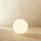 A large Clérachic glowing sphere floor lamp lights a warm plaster room with soft ambient glow.
