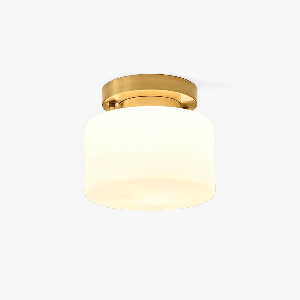 This Clérachic flush-mount ceiling light on a plain white backdrop, a round brass canopy above a white cylindrical glass shade.