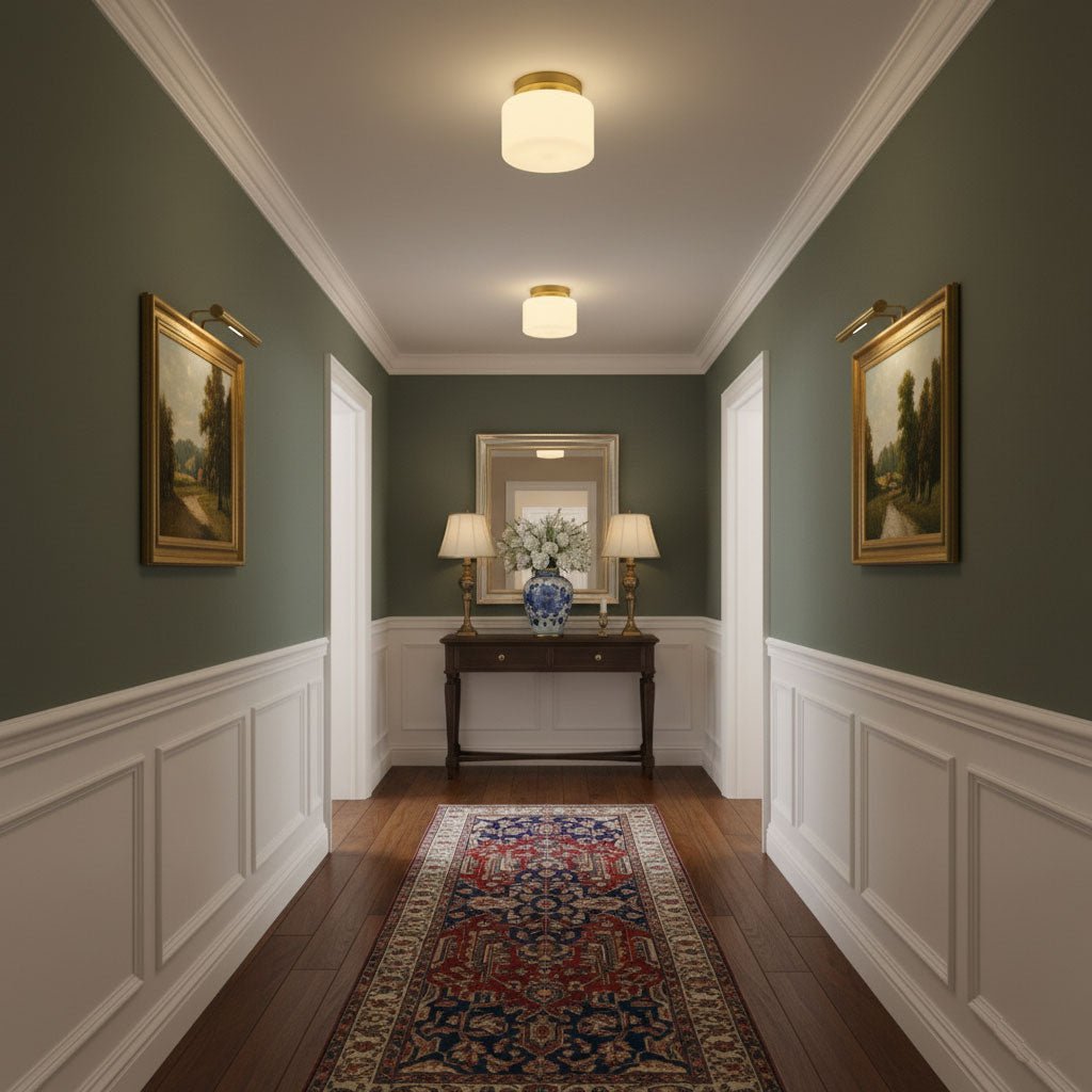 Two Clérachic brass and white glass ceiling lights over a green-walled entry, with a console table, table lamps and gilt-framed landscapes.