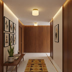 One of two Clérachic flush-mount lights lighting a corridor lined with walnut panelling, a warm cove glow and a wall of geometric prints.