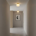 Two small Clérachic flush-mount lights in a narrow grey hallway with a pale tiled floor and a single framed print on the far wall.