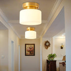 A larger Clérachic flush-mount light in the foreground and a second further down a cream hallway with cornice mouldings and a framed floral print.