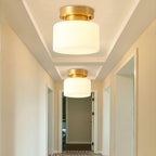 Two Clérachic brass and white glass ceiling lights above a cream hallway, each set in its own stepped ceiling recess.