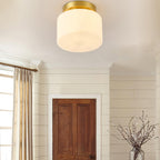Low angle on this Clérachic flush-mount light in a room with a curtained window, white wall panelling and a dark wood door.