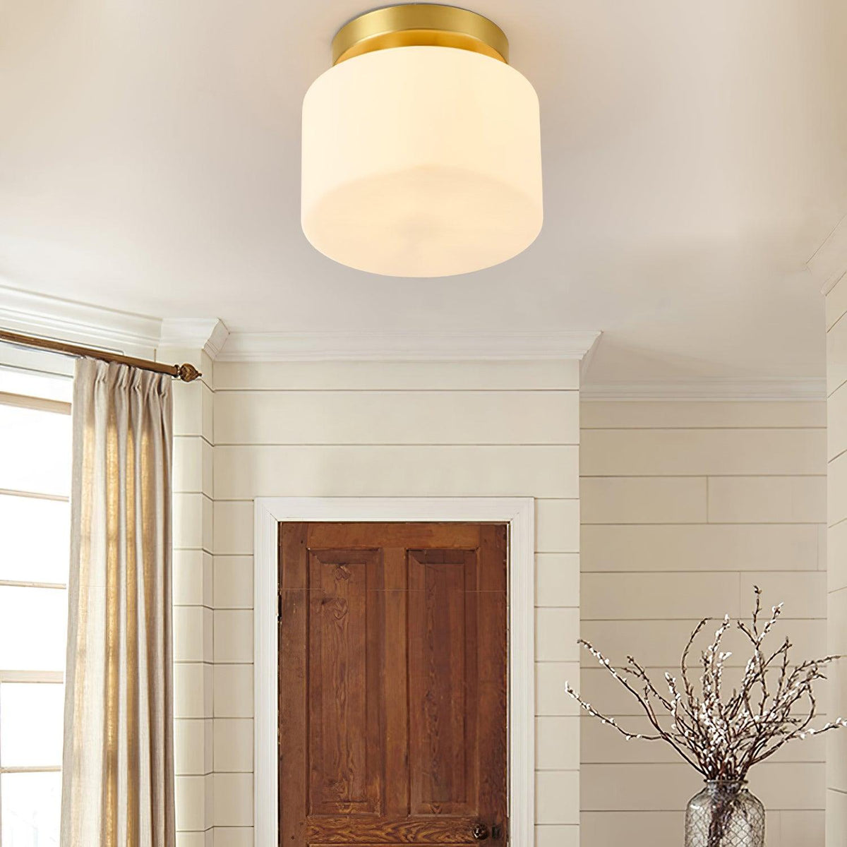 Low angle on this Clérachic flush-mount light in a room with a curtained window, white wall panelling and a dark wood door.