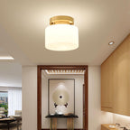 A Clérachic flush-mount light in a modern entry with a recessed downlight, wood cabinetry and a console table below a round-motif panel.
