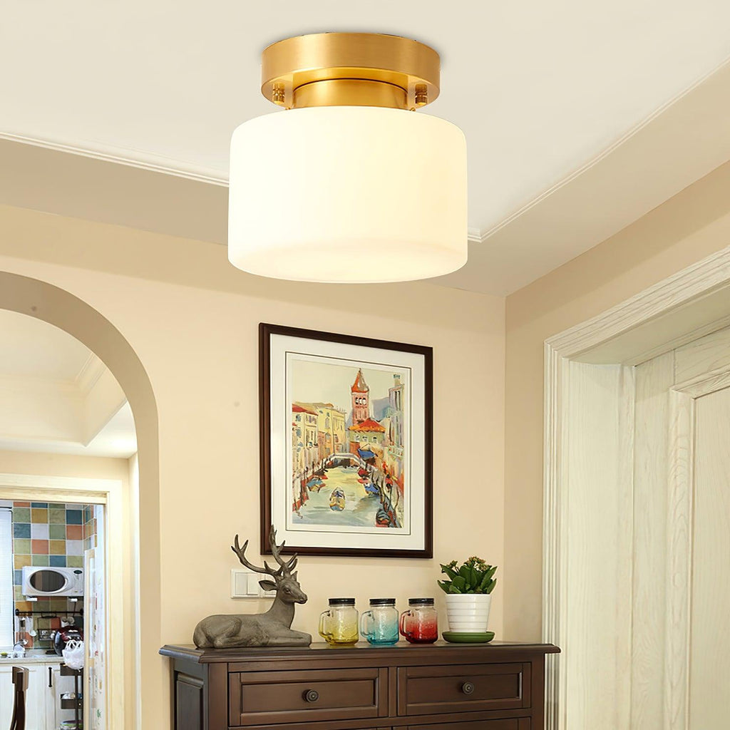 A Clérachic white drum flush-mount light close up, with a cream arched doorway, a framed Venetian print and a dark wooden sideboard below.