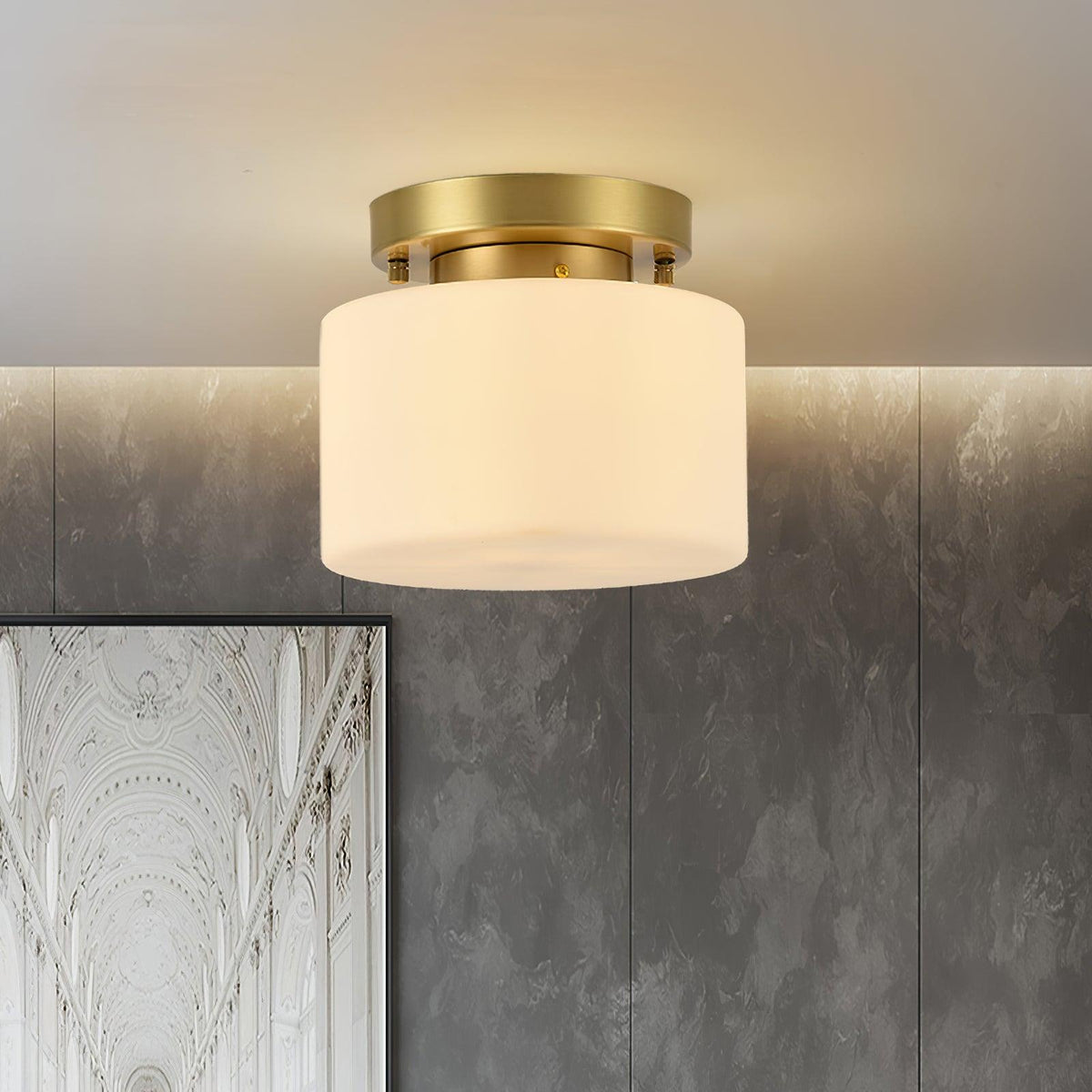 A Clérachic flush-mount ceiling light seen against a grey textured plaster wall, with a white arched architectural print at the lower corner.
