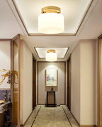 Two Clérachic flush-mount lights hung down a long hallway with a recessed ceiling, patterned marble floor and framed art at the end.