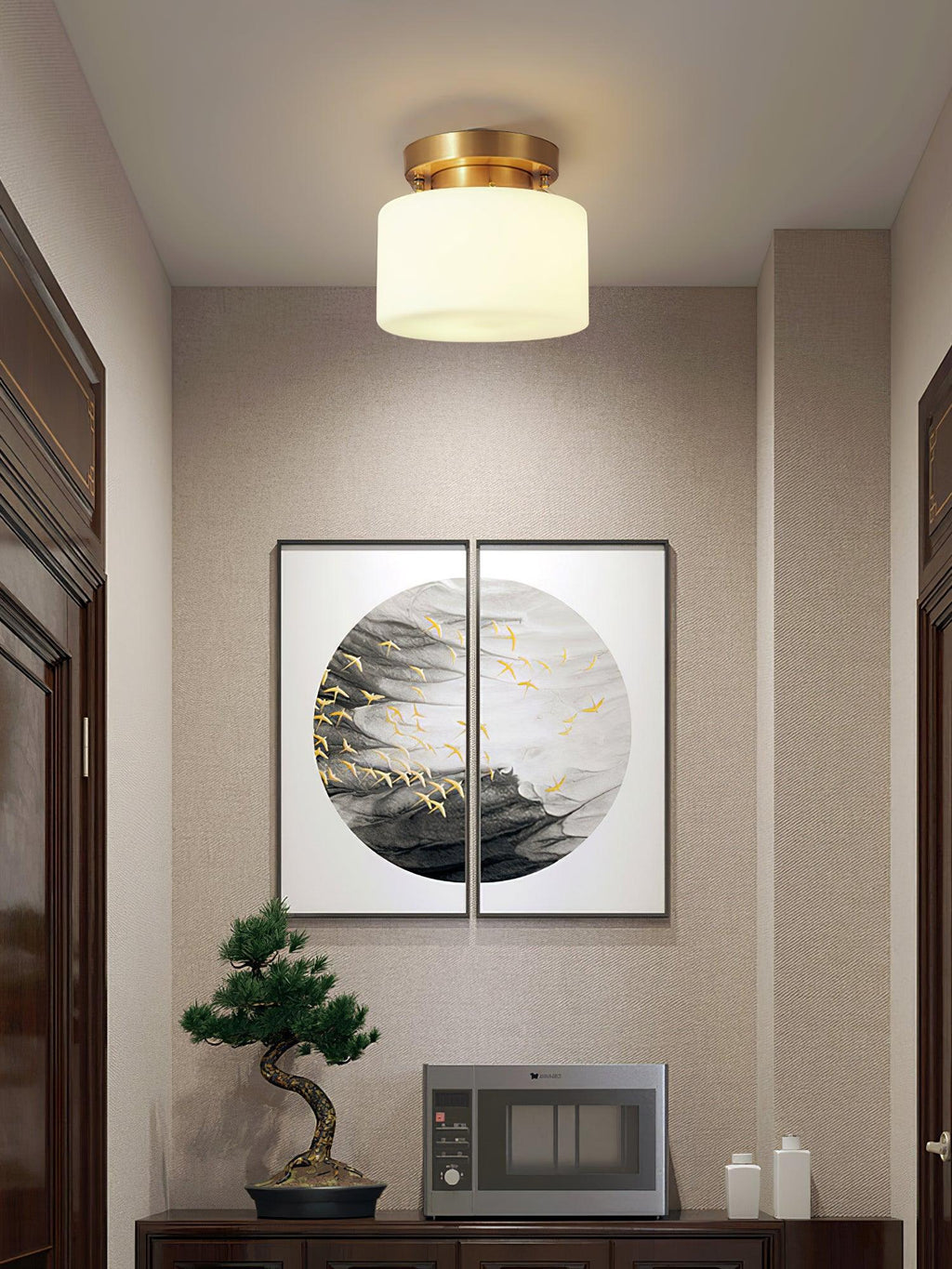 A Clérachic flush-mount light above a hallway with grey-beige walls, dark door frames and a round ink-style artwork over a sideboard.