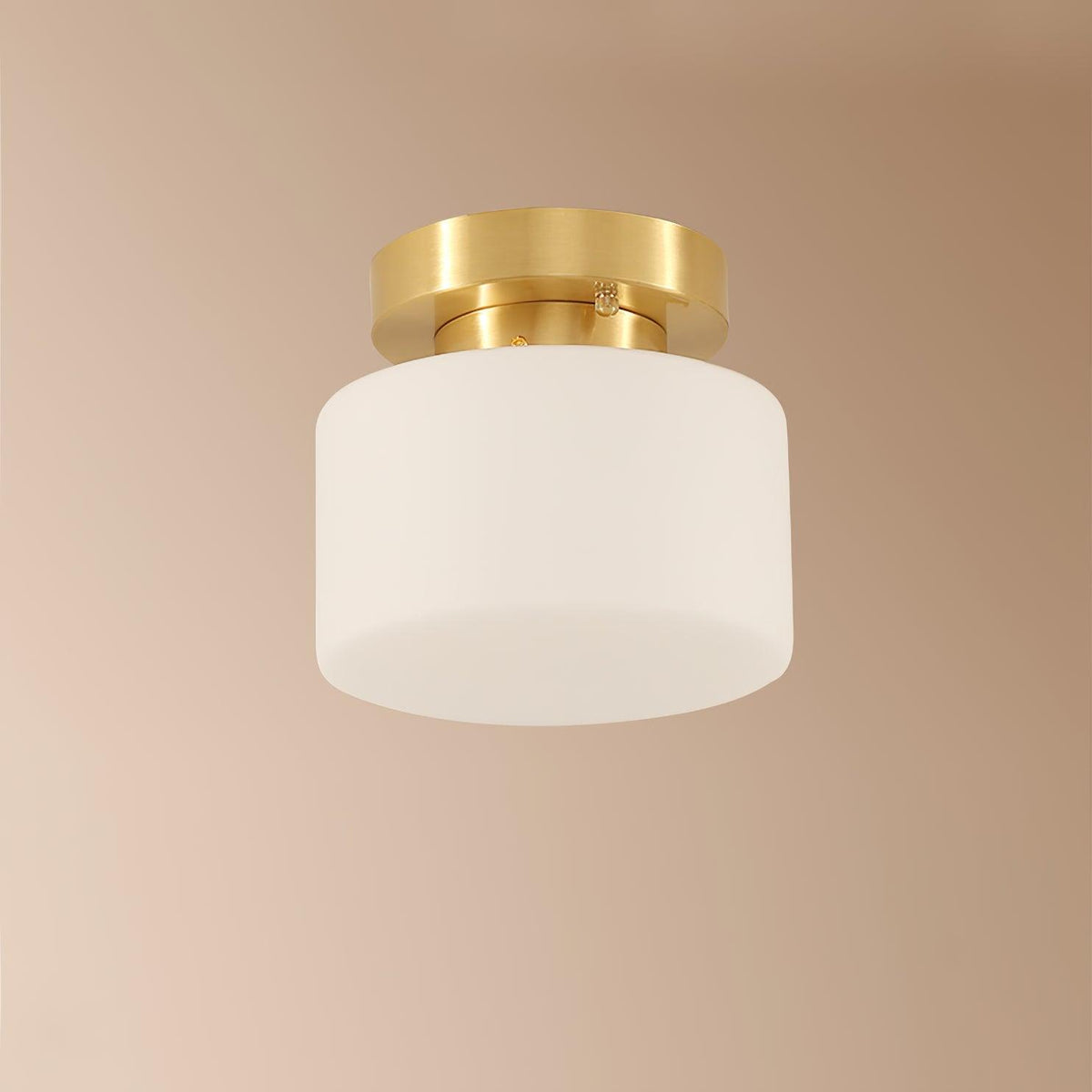 A Clérachic flush-mount light against a blush-beige ceiling, with a frosted white glass shade and a brushed brass canopy.