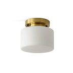 A Clérachic brass and white glass flush-mount light shown on a white backdrop, with the canopy fixings visible against the ceiling.