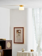 A Clérachic flush-mount light seen from afar on a white ceiling above a round table, with a framed print and a lace curtain.