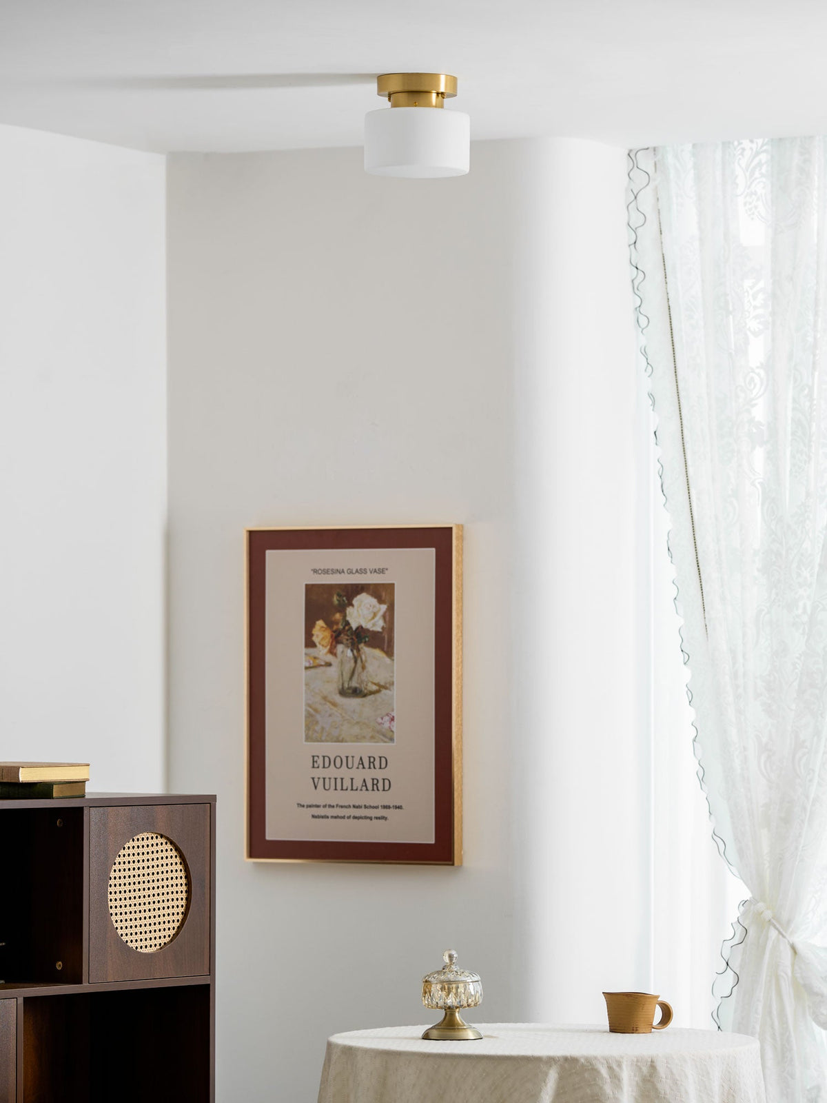 This Clérachic flush-mount light high on a white ceiling above a dark wooden cabinet with rattan panels and a framed print.