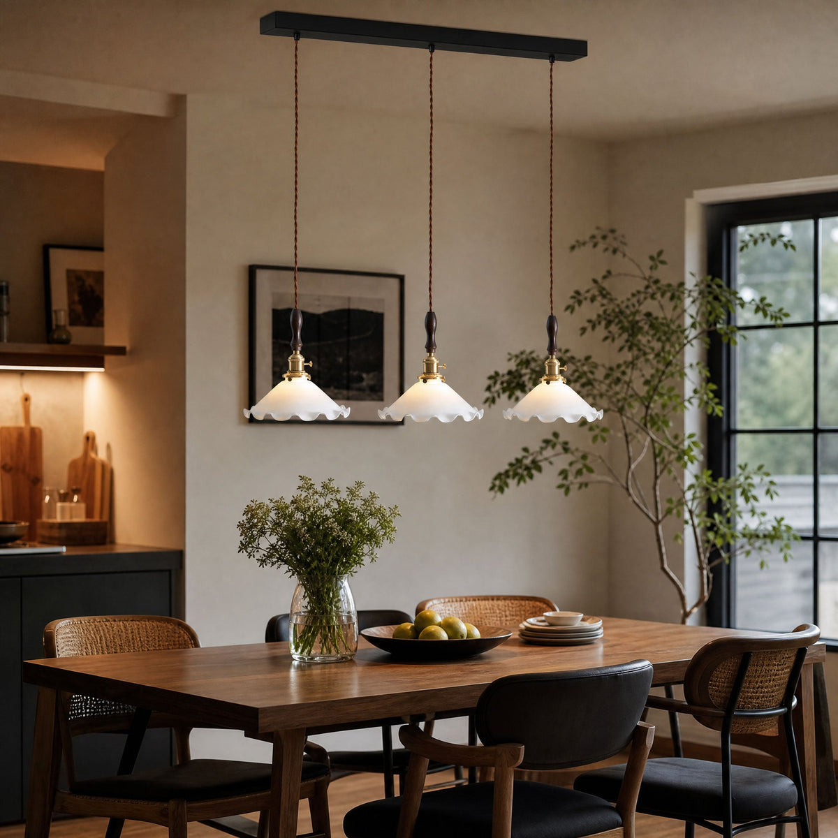 A row of three ruffled glass shades from this Clérachic pendant light hangs above a timber dining table with black cane chairs.