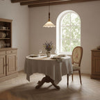 This Clérachic pendant light hangs beside an arched window above a round table with a linen cloth and a small bunch of lavender.