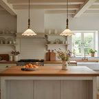 Two of this Clérachic pendant light hang over a wood-topped island in a cottage kitchen with open shelves and a bowl of oranges.