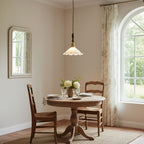 This Clérachic pendant light hangs above a round table set for two in a room with an arched window and a framed mirror.