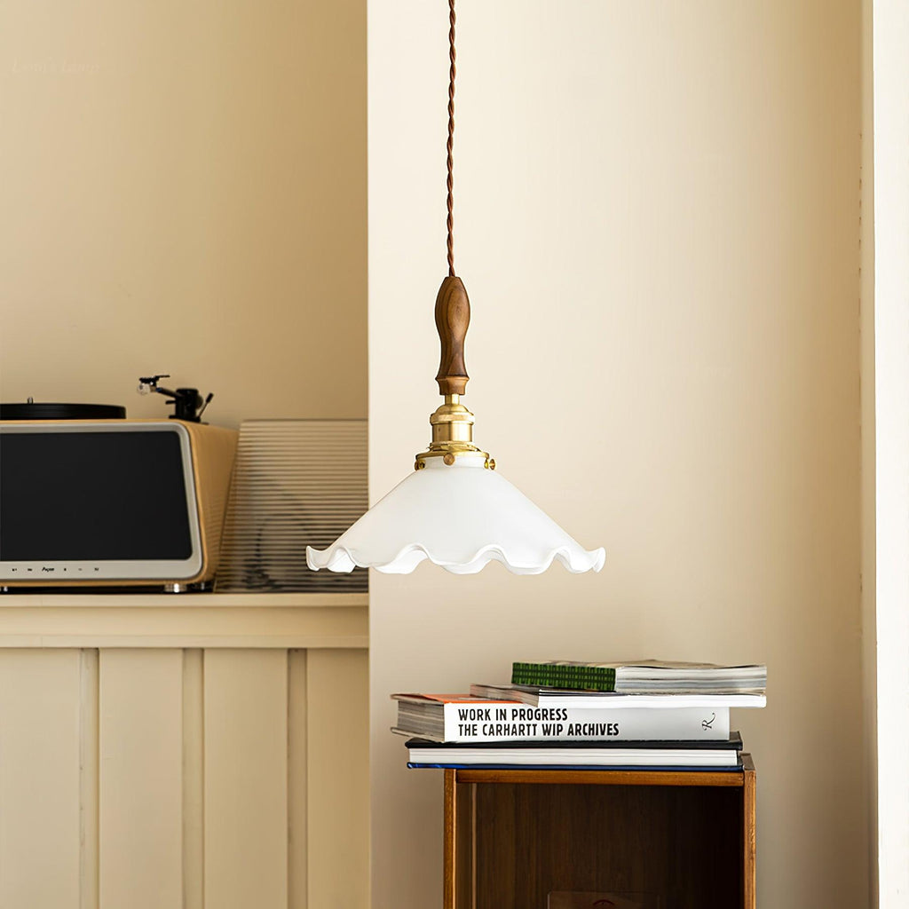A Clérachic pendant light hangs in a cream corner above a stack of books, with a retro radio on a shelf behind.