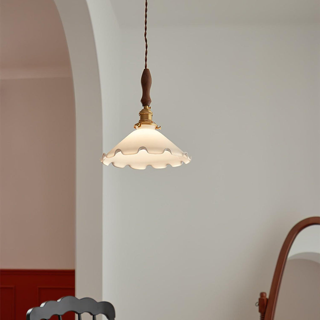 This Clérachic pendant light hangs against a grey wall beside an arch, with a deep red wall below at the edge of the frame.