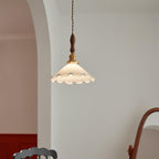 This Clérachic pendant light hangs against a grey wall beside an arch, with a deep red wall below at the edge of the frame.