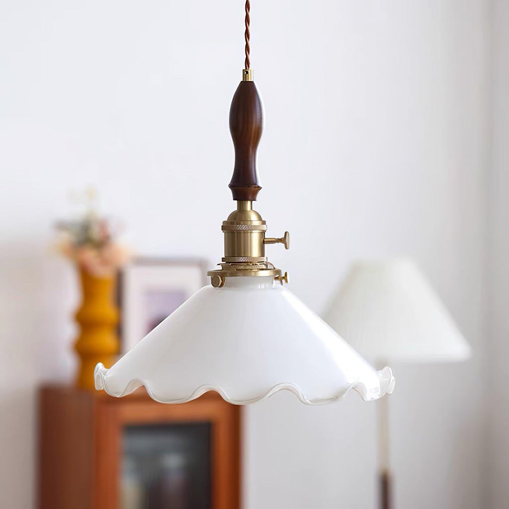 Seen from a slightly different angle, this Clérachic pendant light shows the brass turn switch on its socket above a ruffled shade.