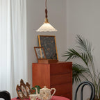 Seen from below, this Clérachic pendant light hangs above a teak chest of drawers with a framed print and a pot of tea beside it.