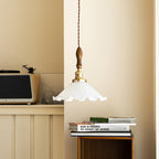A Clérachic pendant light hangs in a warm cream corner above a retro radio and a stack of books.