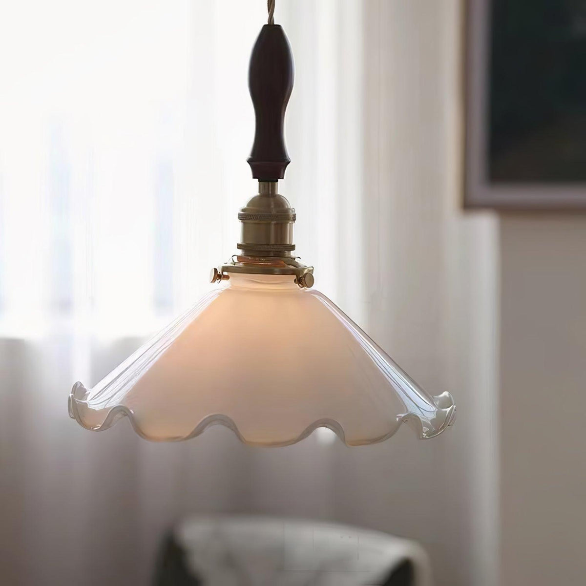 Softly lit, this Clérachic pendant light glows in front of sheer white curtains with a faint armchair visible behind.