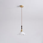A Clérachic pendant light hangs from a round brass ceiling plate on a twisted cord, shown small against a pale ceiling.