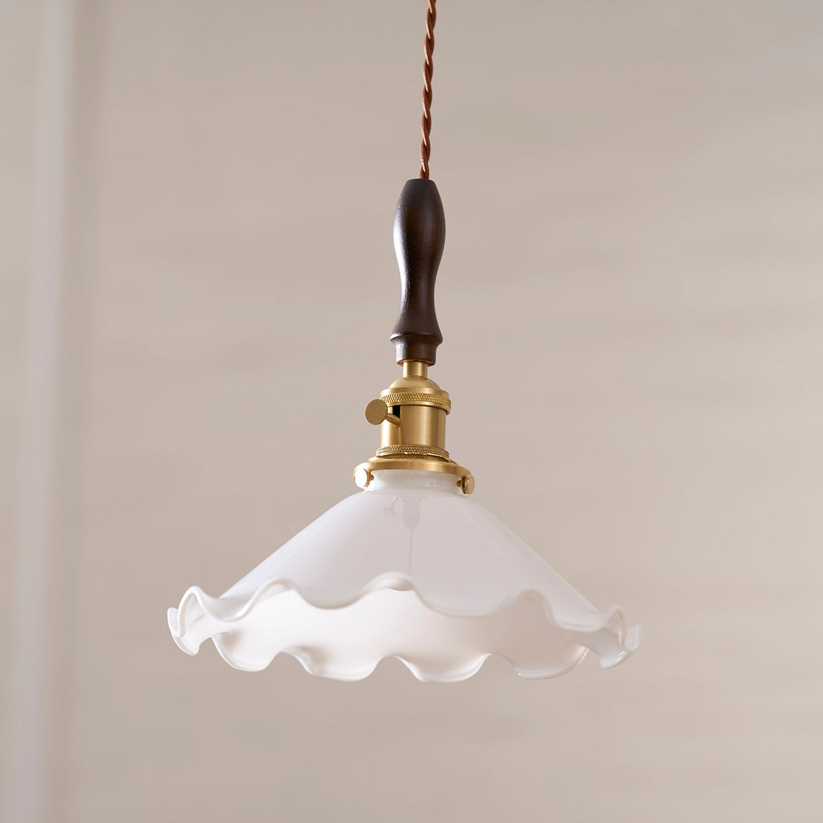 A slightly lower view of this Clérachic pendant light on a beige wall, the wavy rim of the shade clearly visible.