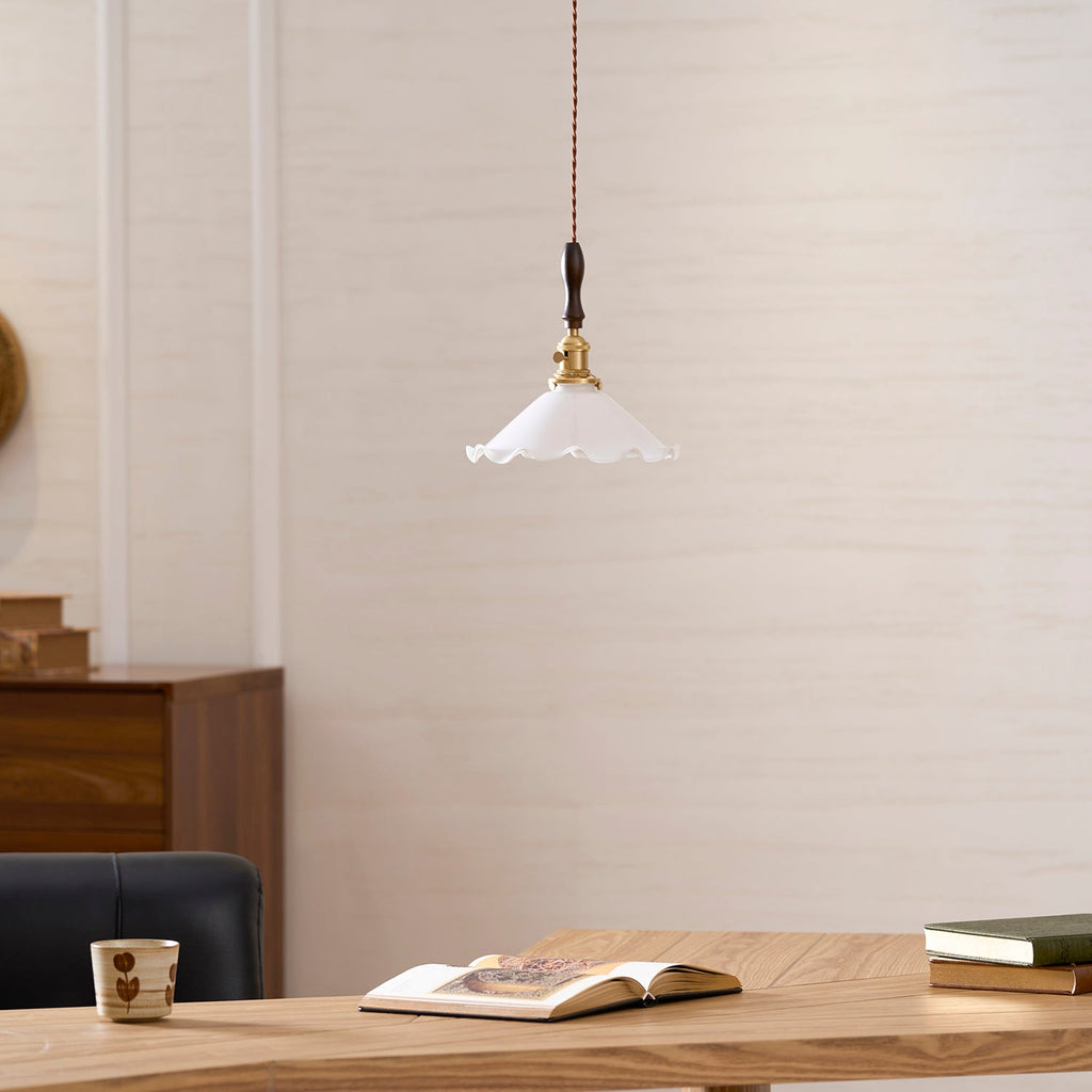 This Clérachic pendant light hangs at desk height above an open book and a mug, with a leather chair back at the left.
