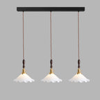 Three Clérachic pendant lights hang from a long black bar on twisted cords against a grey backdrop.