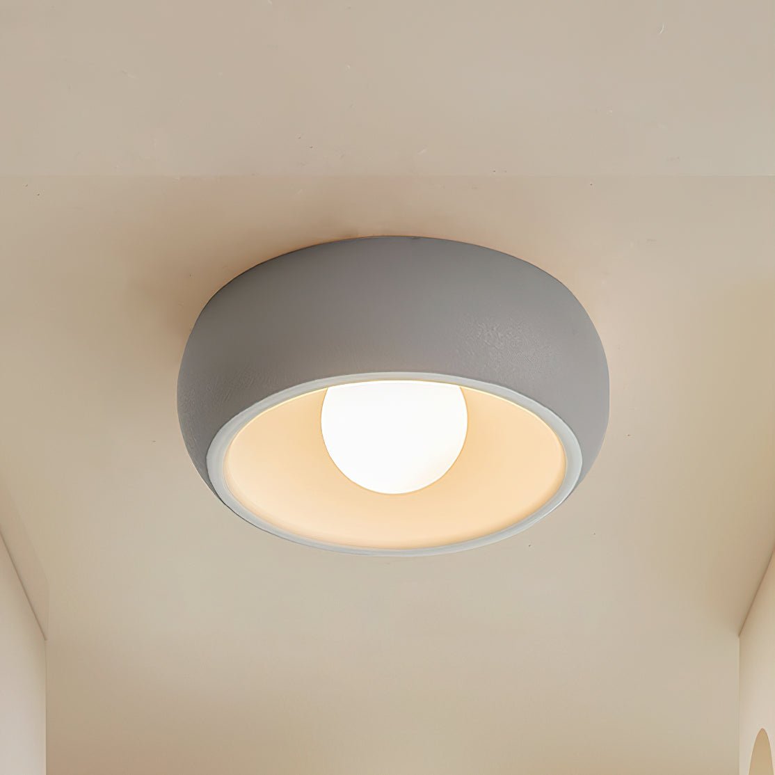 Grey Clérachic ceiling light on a cream ceiling, a rounded grey bowl with a white inner rim and a lit round bulb.
