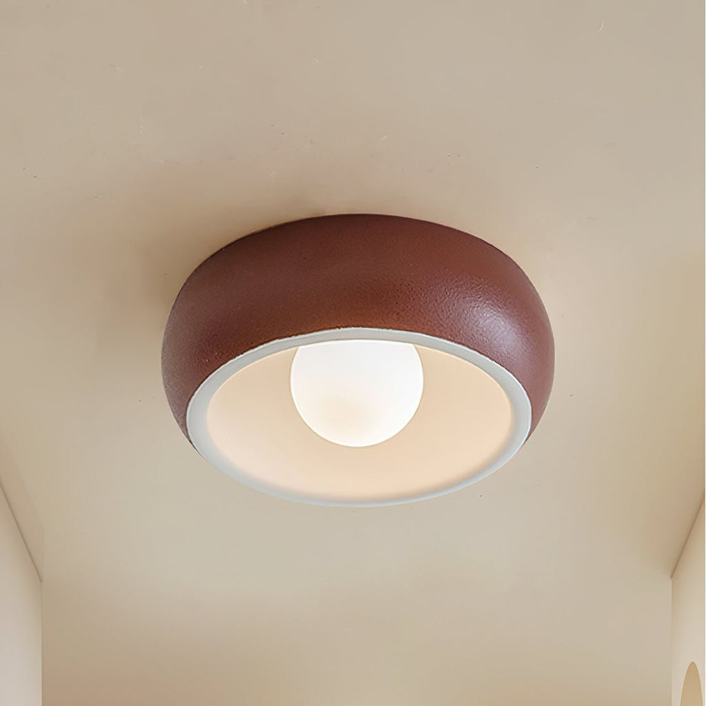 Red Clérachic ceiling light with a textured terracotta-red outer bowl and a white inner rim around a lit round bulb.